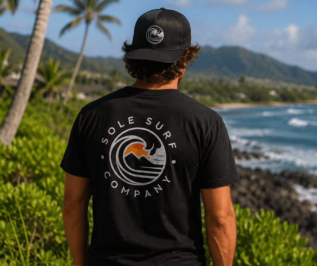 Person wearing a black 'Sole Surf Company' t-shirt with a scenic ocean view in the background.