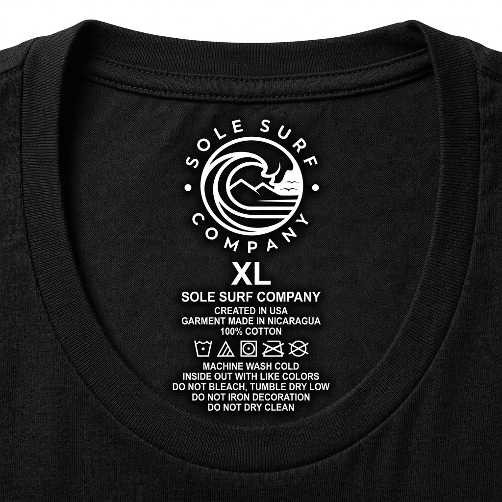 Close-up of the inside collar of a black round neck T-shirt showing a white printed Sole Surf Company logo and care instructions for size XL.