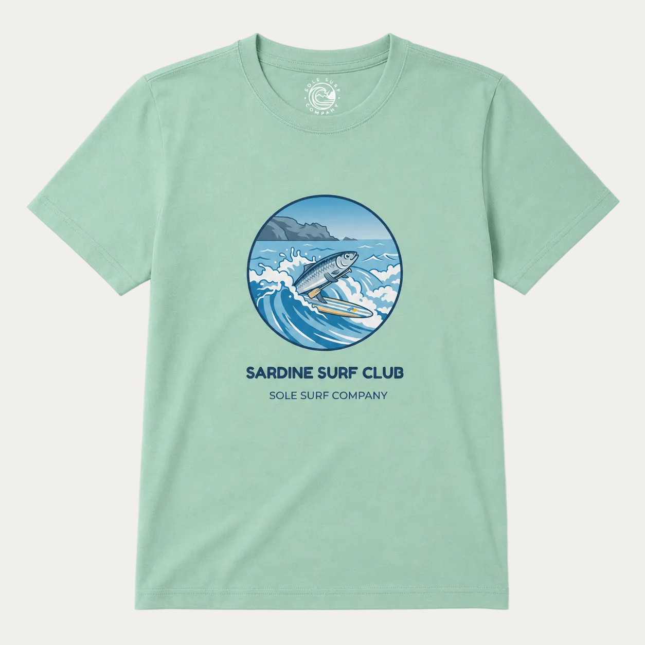 A mint green crewneck t-shirt featuring a circular graphic of a surfer riding a wave, with the text 'SARDINE SURF CLUB' and 'SOLE SURF COMPANY' printed below it, displayed on a light cream background.