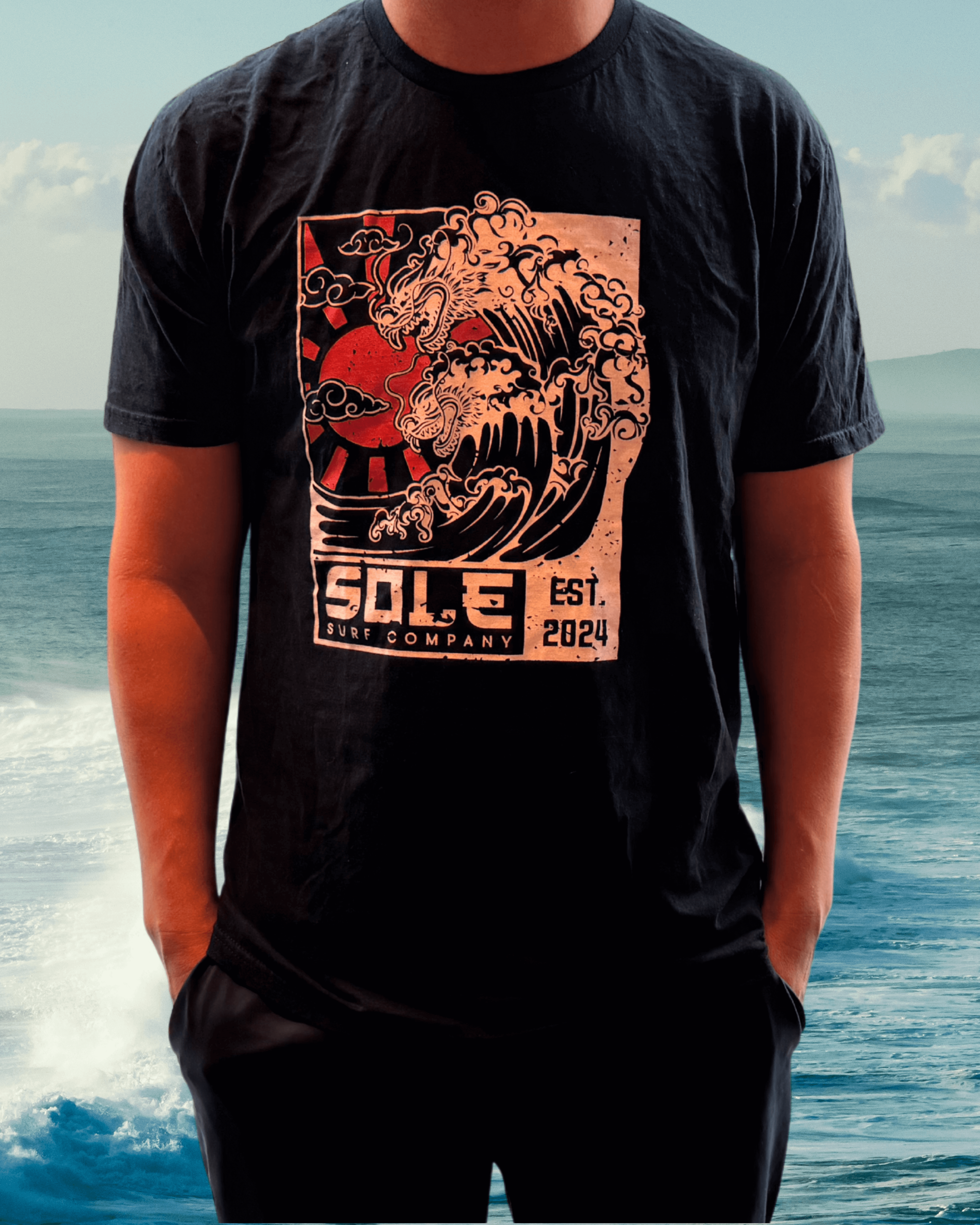 Black tee with hand-drawn Japanese dragon and wave design, showcasing coastal art and surf culture.