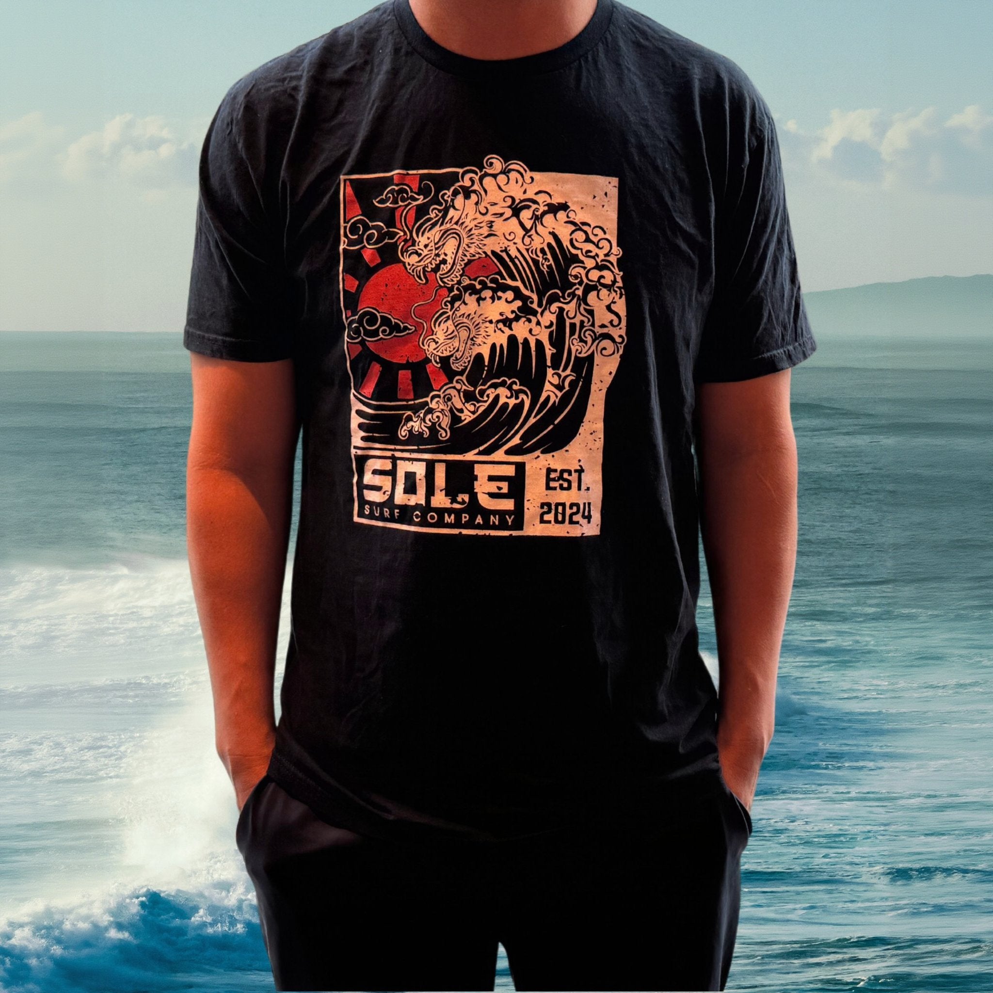 Black tee with hand-drawn Japanese dragon and wave design, showcasing coastal art and surf culture.