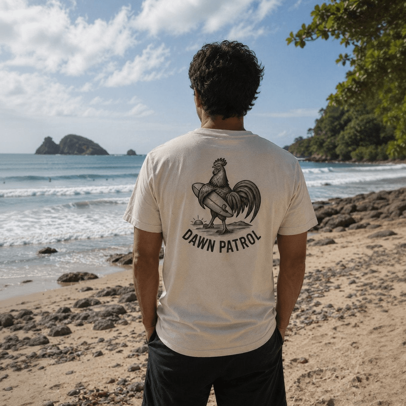 Person wearing a t-shirt with 'Dawn Patrol' design on a beach
