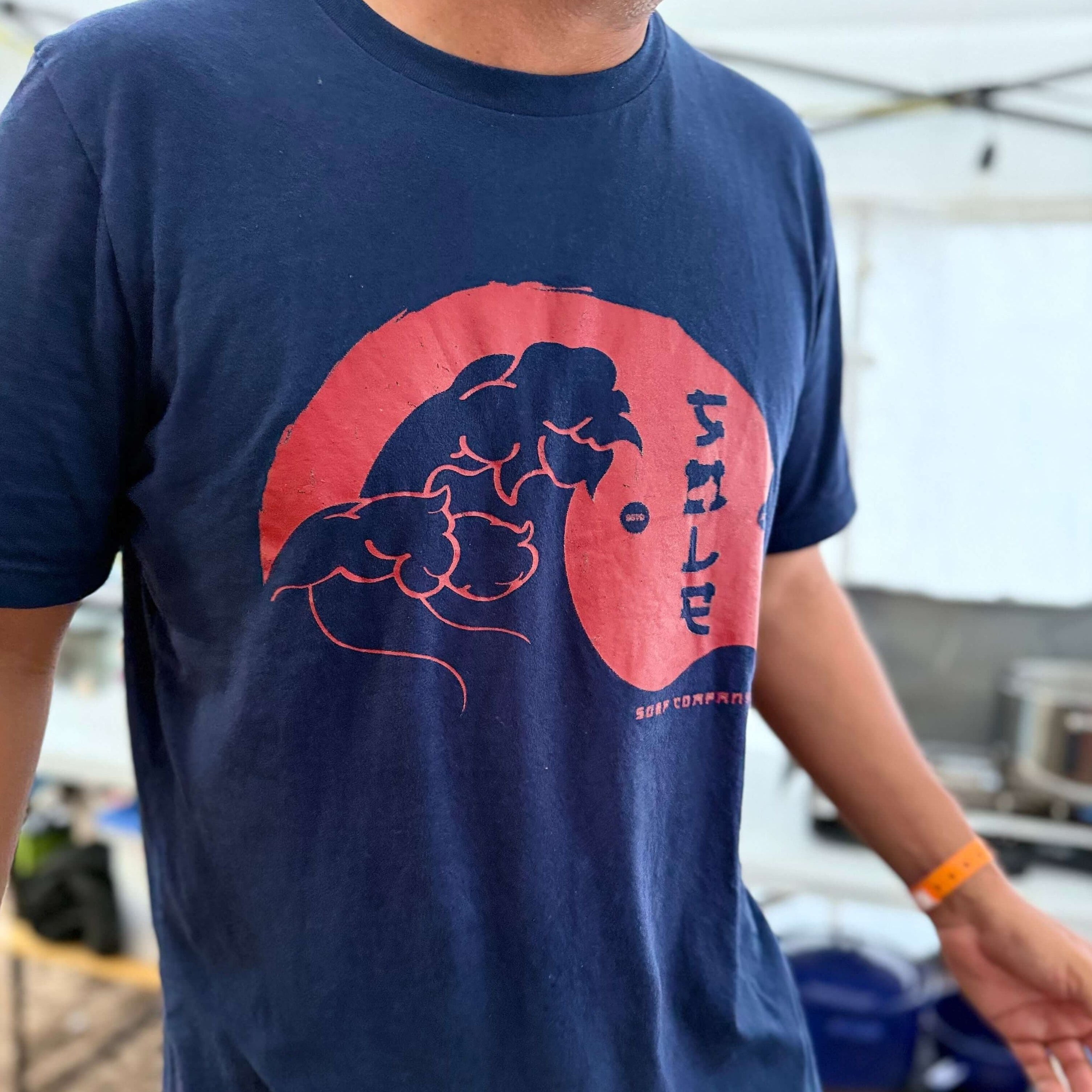 Person wearing a navy blue t-shirt with a red and black graphic design.