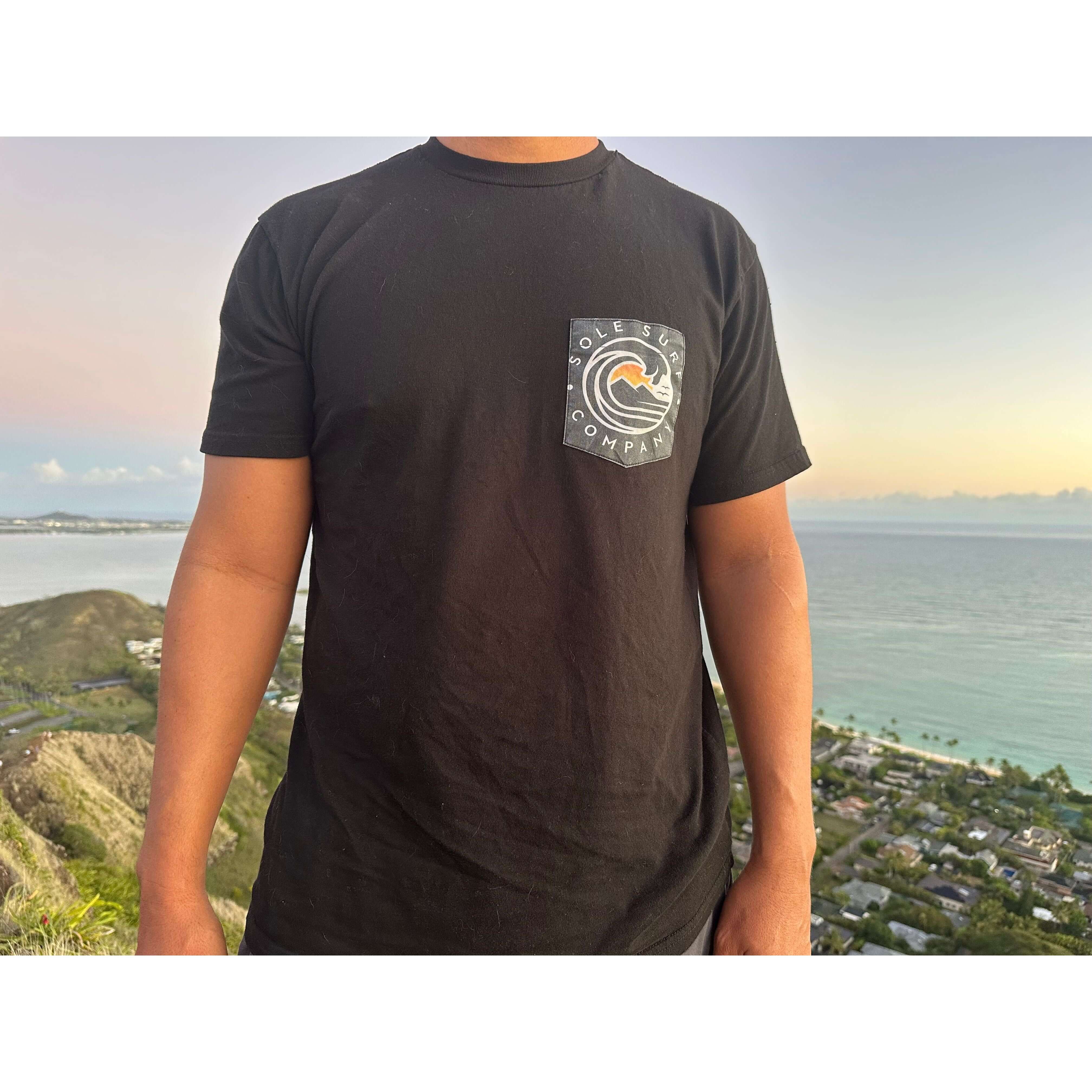 Black pocket t-shirt featuring a stylish logo, perfect for casual wear or beach outings, made from soft, lightweight cotton.