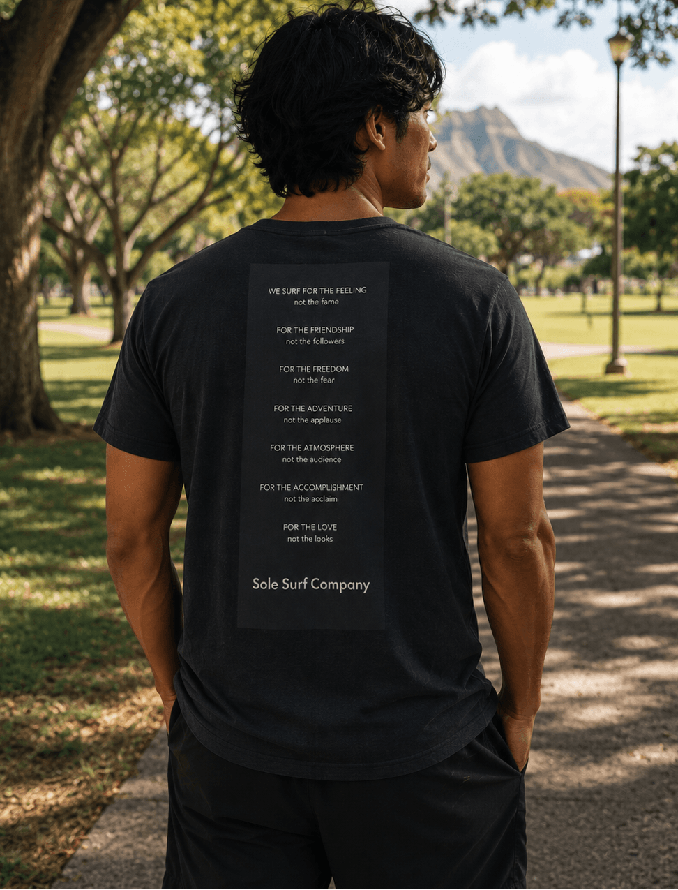 Person wearing a black t-shirt with text on the back in an outdoor setting