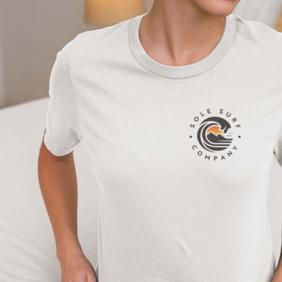 Close-up of a woman wearing a light tee with the Sole Surf Company logo, showcasing casual style and comfort.