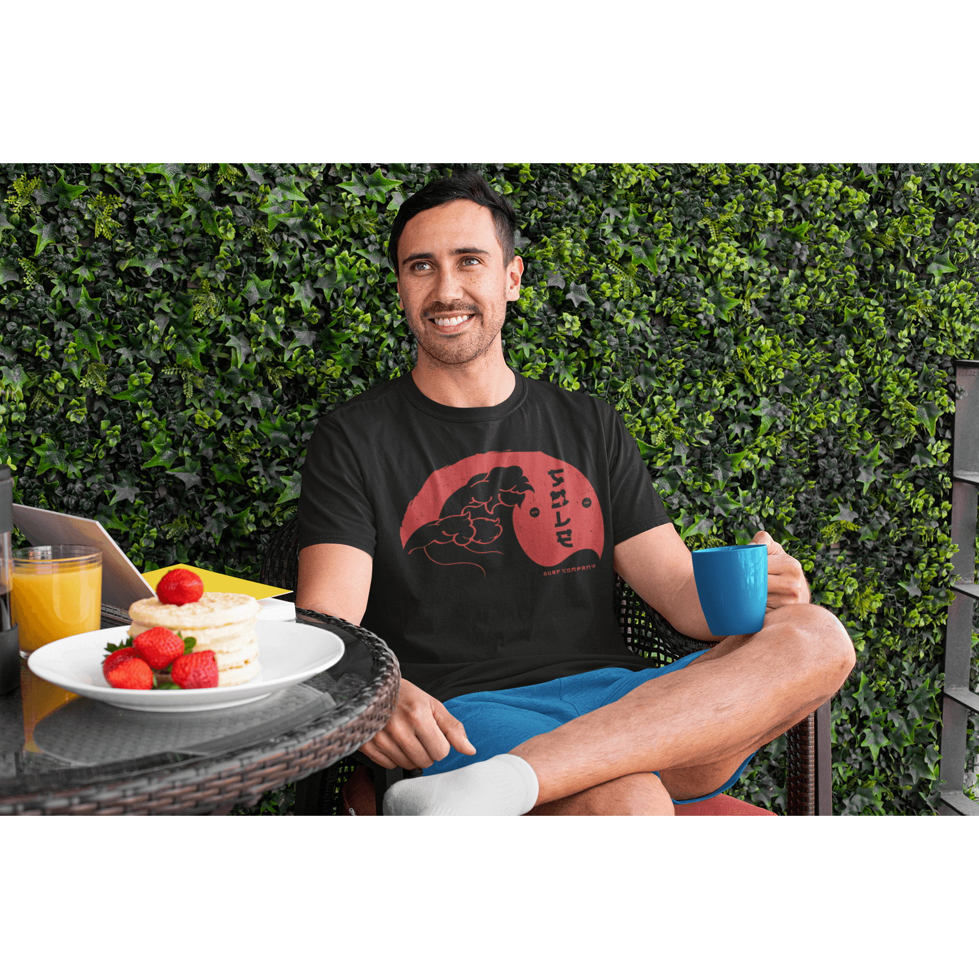 Man wearing a Japanese Wave design T-shirt, enjoying breakfast outdoors in a serene garden setting.